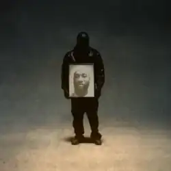 Ty Dolla Sign completely covered in a black leather jacket and mask. He is holding a picture of his brother "Big TC" and standing in the center of a graduated color background going from tan, to cerulean, to black at the top.