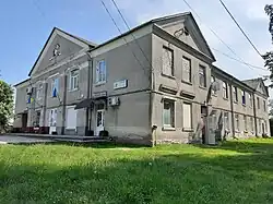 A picture of a building with grey side paneling and a Ukrainian flag