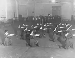 Women kneeling in rows holding out clubs
