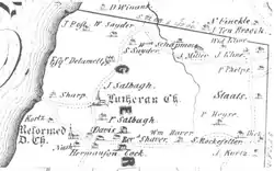 A black and white map with Old English style type showing an area by the side of a large river on the left, with many small houses and churches