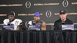 Football players and coaches giving a press conference