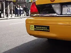 DIAL 311 bumper sticker on a New York City taxi.