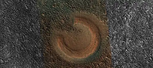 Close view of mud volcano, as seen by HiRISE. Picture is about 1 km across. This mud volcano has a different color than the surroundings because it consists of material brought up from depth. These structures may be useful to explore for remains of past life since they contain samples that would have been protected from the strong radiation at the surface.