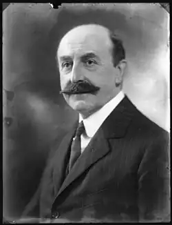 Monochrome portrait photograph of Sir Anderson Montague‑Barlow. He is shown in three-quarter profile wearing a suit, white shirt, and tie. He has a large moustache and a bald pate.