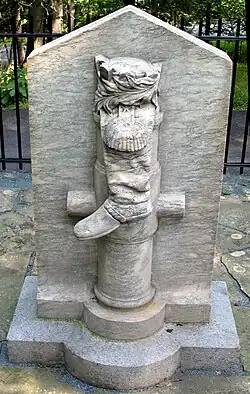 a white marble slab with the carved relief of a howitzer gun and soldier's boot