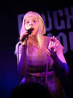 Aurora singing holding a microphone