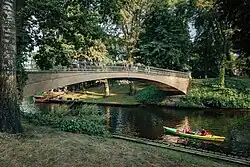 A bridge over Riga City Canal in the Bastejkalns park, with people seen boating on the canal