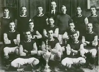 A black and white picture of Burnley posing behind a football trophy