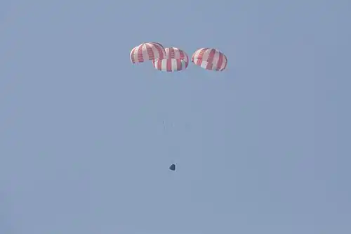 Dragon descending under parachutes