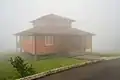 A mountain lodge is shrouded in thick fog in daytime