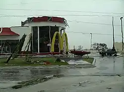 Photograph of a fast food restaurant showing some damage to its façade with debris on the adjacent road