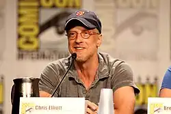 A smiling man wearing glasses and a cap.