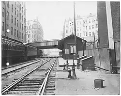 A wooden railway station next to a below-grade rail line in a city