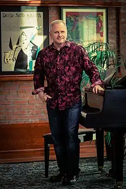 Musician David Slater standing next to a piano