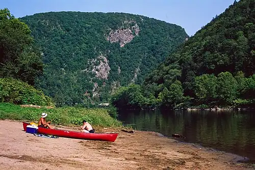 Two recreationalists rest in a beached canoe at the base of Mount Tammany