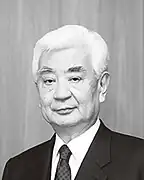 upper-body shot of older man with white hair, dark suit and tie