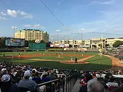 A baseball game on a green field as seen from the seating bowl behind home plate