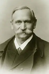 A man with a large white mustache wearing a suit and a large coat