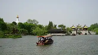Boat on a lake with pavilions and a bridges on the shore