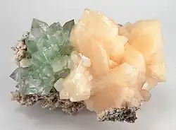 Clustered on a matrix of white chalcedony are a group of light salmon stilbite crystals; adjoining is a cluster of mint green fluorapophyllite crystals