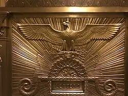 Detail of a gilded mailbox in the lobby, with an eagle carving