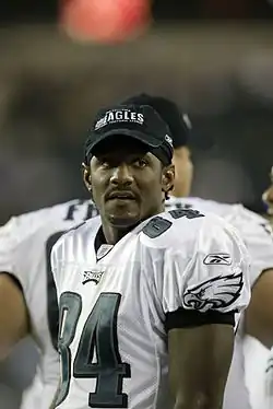 Mitchell standing on the sidelines during a preseason game with an Eagles cap on.