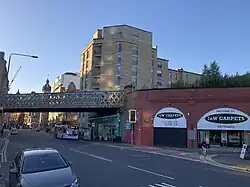 Street and assign underneath railway viaduct. On the right of the image, The rail bridge over the street transitions to an elevated Brick viaduct with arches