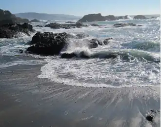 Small waves breaking on a beach along a rocky shoreline