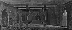 A monochrome illustration of a stone and brick-walled room. An open doorway is to the right. The left wall contains equally spaced arches. The right wall is dominated by a large brick arch. Three arches form the third wall, in the distance. The floor and ceiling is interrupted by regularly spaced hexagonal wooden posts. The ceiling is spaced by wooden beams.