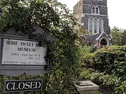 The foreground sign is at the entrance to the Home Sweet Home museum; the building in background is St. Luke's Church