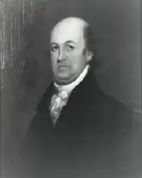 A balding man wearing a black jacket and white shirt