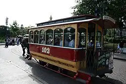 A red and white enclosed horse-drawn streetcar hitched to a draft horse