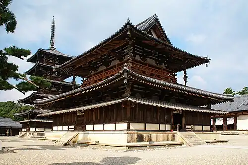 A large wooden building with a hip-and-gable main roof and a secondary roof giving the impression of a two-story building. Between these roofs there is an open-railed veranda surrounding the building. Below the secondary roof there is an attached pent roof. Behind the building there is a five-storied wooden pagoda with surrounding pent roof below the first roof.