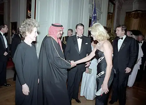 Ivana Trump and King Fahd shake hands, with Ronald Reagan standing next to them smiling