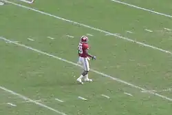 American football player waiting to field a punt on a green field.