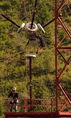 Contractors working on feed bus tower. The long insulator strings and corona rings are needed to withstand the very high voltage on the antenna.