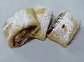 Roll shaped kaab al-Ghazal cookies stuffed with date paste and walnuts and topped with powdered sugar