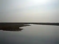 View of mud expanse and flooded area after rainfall