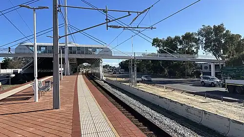 Train station island platform with a footbridge and large shelter