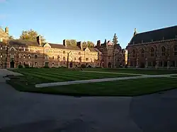View over Liddon Quad covered in grass from the Chapel looking towards the Porter's Lodge. The building is the famous red brick.