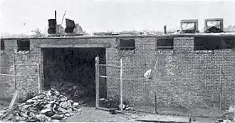 A pile of metal cans outside a fire-damaged brick building