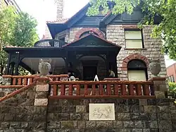 Exterior photo of 1889 era stone house with dark trim owned by Margaret Brown