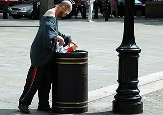 Man searching a London rubbish bin for food.