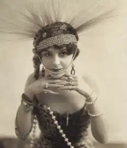 A white woman wearing a spiky headdress and pearls