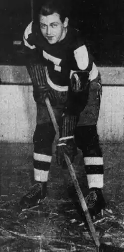 Black and white photo of a hockey player holding a hockey stick, in uniform with a number 7 on the front