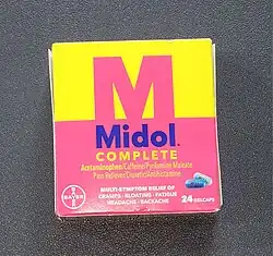 A box of Midol from 2023. The box features a yellow background and pink foreground with an M silhouetted against the background. The bottom of the box depicts the pills and describes the drug.