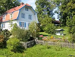 White, two-story home with attic and a garden