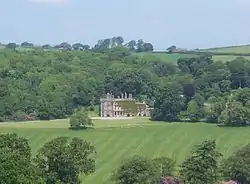 open grassland in front of country house, with trees in the background