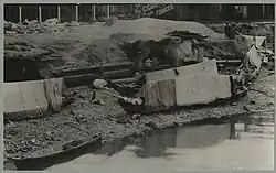 A waterside camp, with a canoe and tent near the base of a large building