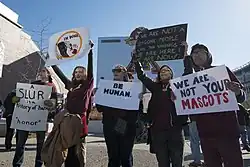 photograph of several protesters with signs opposing the use of the name Redskins and the logo of a Native American by the Washington NFL team in Minneapolis, Minnesota, November 2014